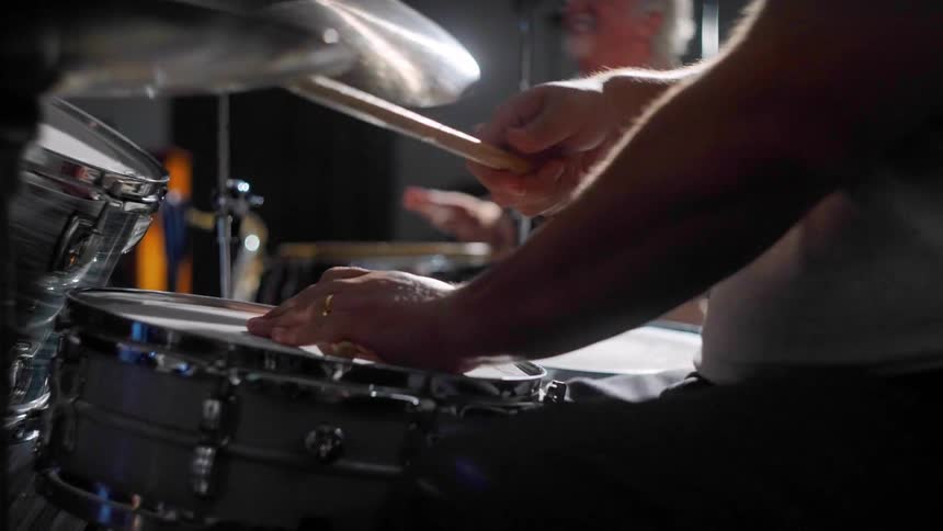 Two people sitting playing drums