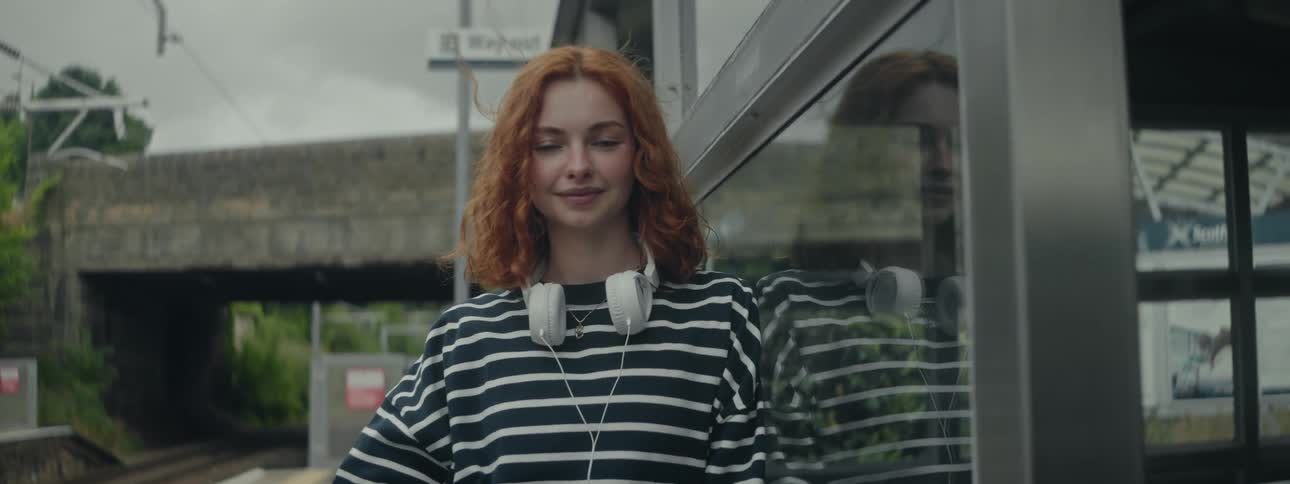 Redheaded woman standing next to a window in an outdoor space