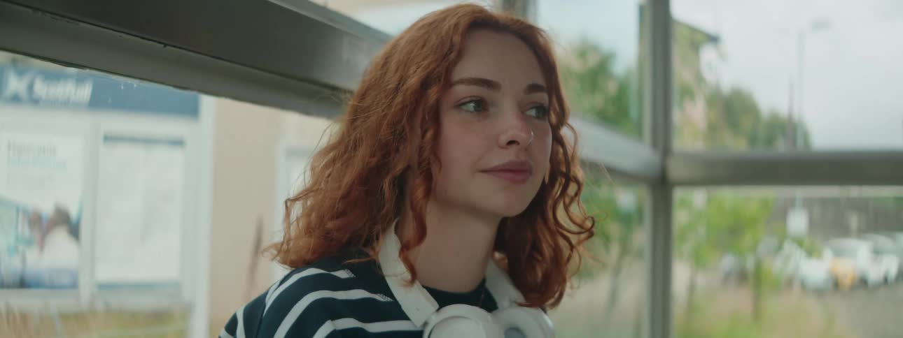 A female wearing headphones sitting inside a building in spring