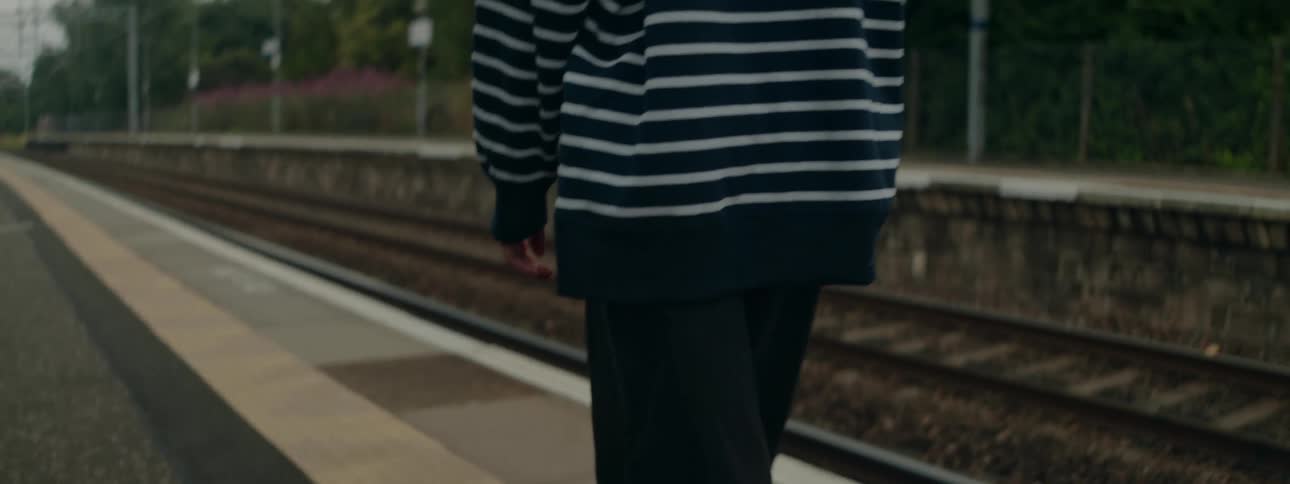 Closeup of a persons legs walking alongside a train track