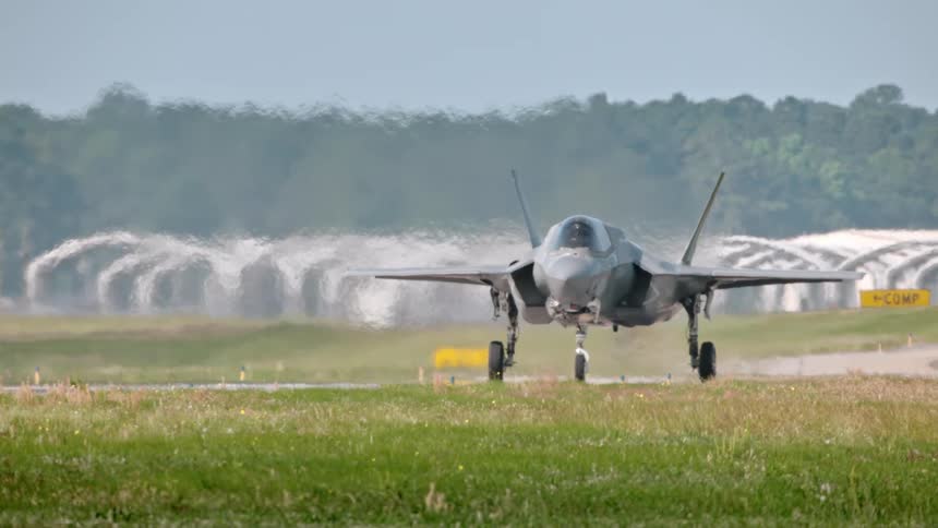A military plane travels down a runway on a sunny summer day
