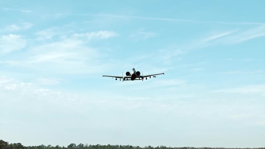 An a 10 thunderbolt ii warplane flies low against a clear blue sky