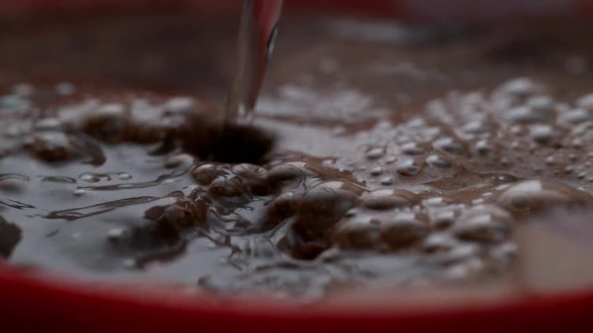 Boiling water is poured into a cup of coffee in slow motion
