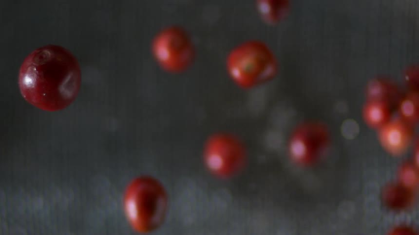 Red fruits suspended in the air with water droplets