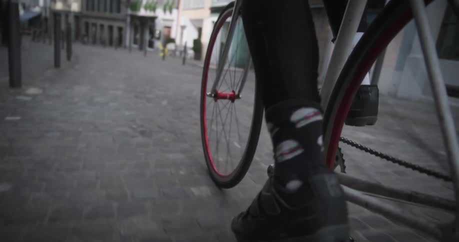 Legs of a cyclist pedaling along an urban road