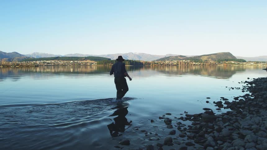 A fisherman wades through a lake