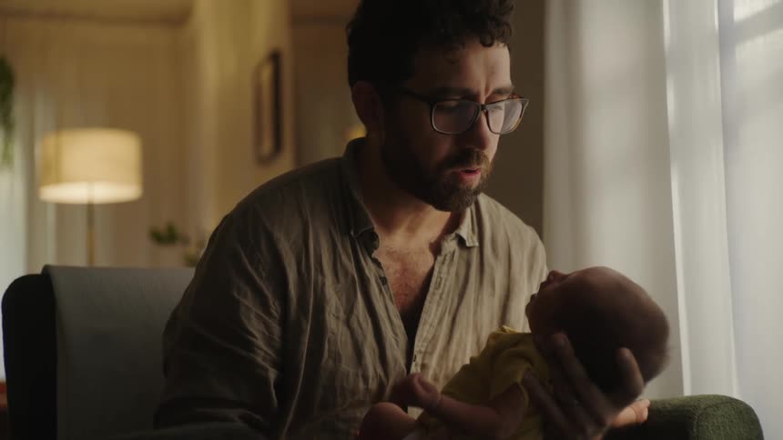 Father sitting in an armchair holding a baby on his lap