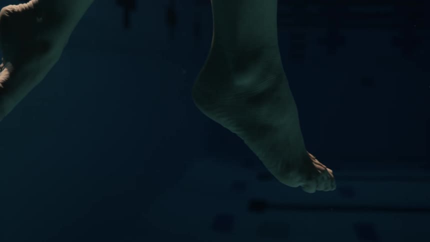 Light shines onto the feet of someone threading water in a pool