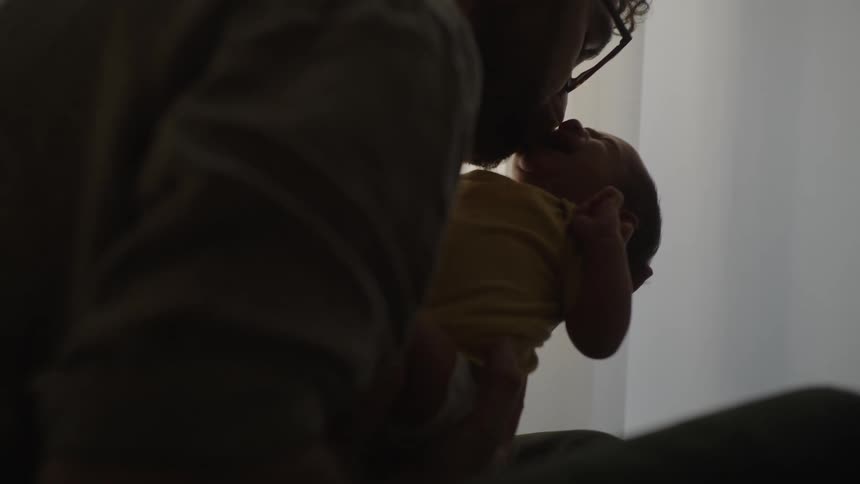 Father holding a baby in his arms and giving a kiss