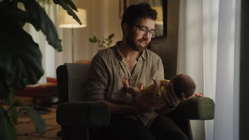 Father sitting in an armchair interacting with his baby daughter