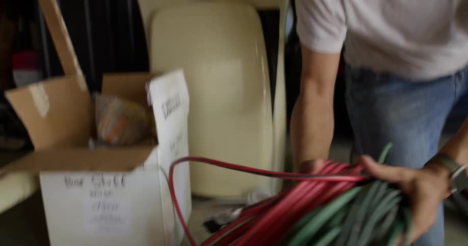 Man lays multiple bundles of cords on the floor ina storage area