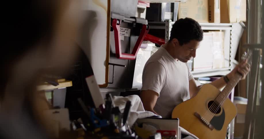 A man examines the guitar and strums the strings