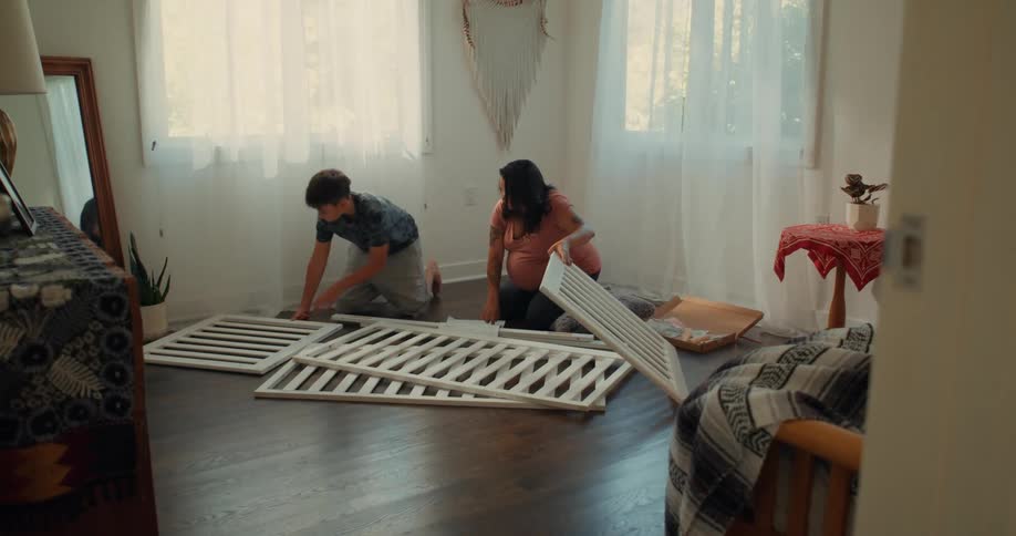 Woman and a boy setting up a crib in a bedroom