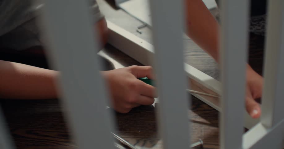 Mother and son assemble a crib using a screwdriver