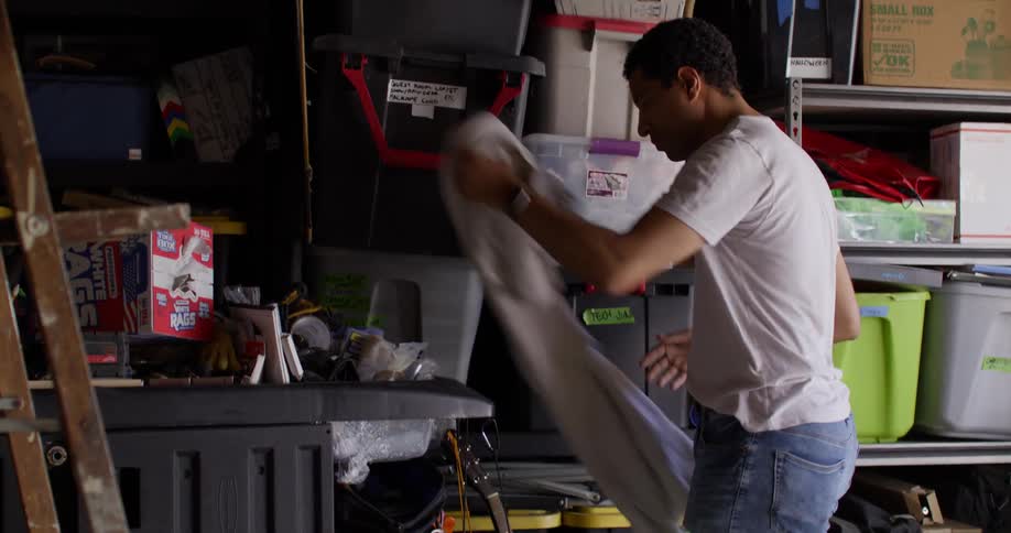 Man picking up a guitar from a crate warehouse