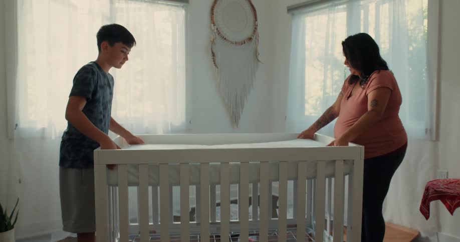 Pregnant mother with the help of her son placing a mattress in the crib