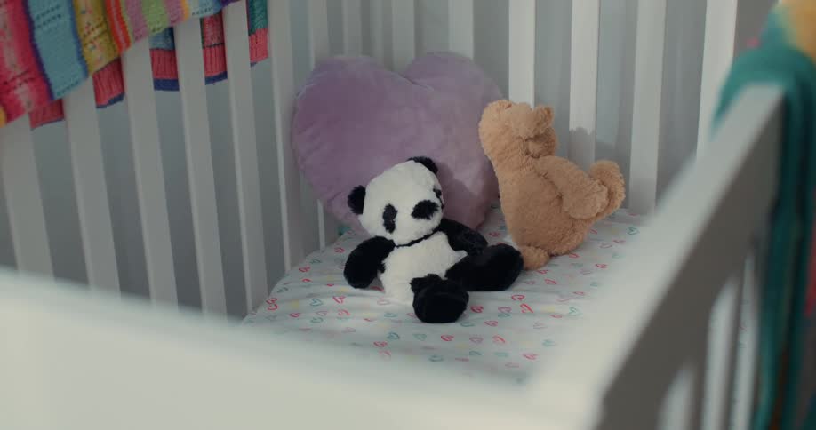 Two teddy bears inside a crib