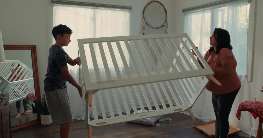 A pregnant mom and her son turn the crib upside down in the room