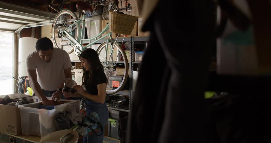 A couple sorting through boxes on a cluttered garage