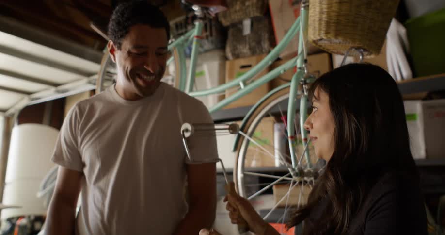 Woman holding a paint roller and playfully passing it over a man next to her