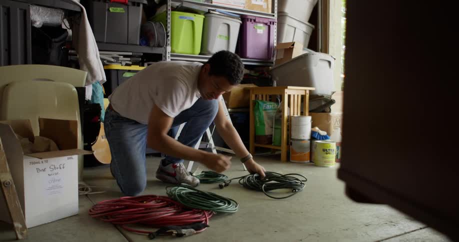 A crouching man is placing a green rope that was on his arm on the ground