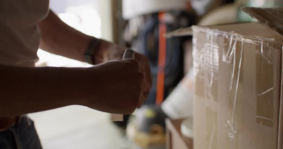 A man uses a piece of tape to label a box