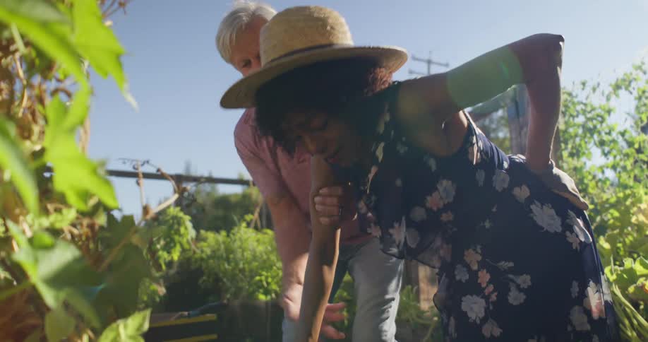 A man helps a woman stand up in the garden