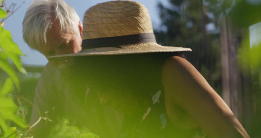 Man helping a woman to stand up while they are in a vegetable garden