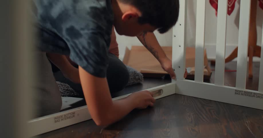 Son helping pregnant mother assemble a crib