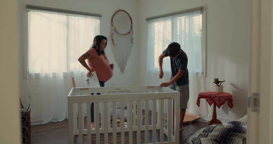 A mother talks with her son who is building a crib