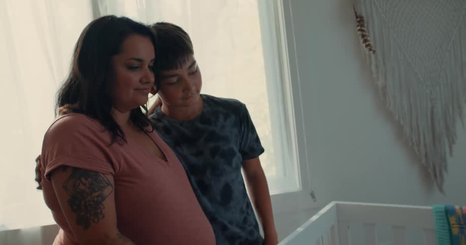A mother and son hug while looking at a crib