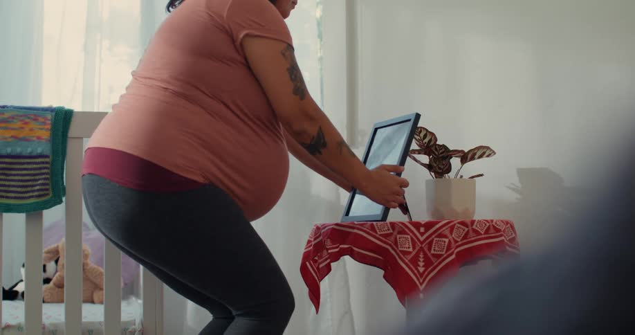 A pregnant woman puts a photo frame on the small table