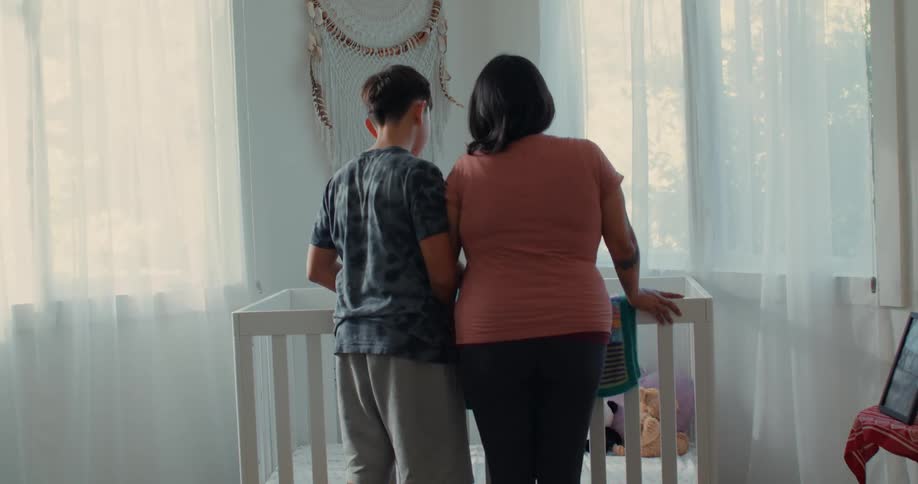 Pregnant mother hugging her baby next to a crib