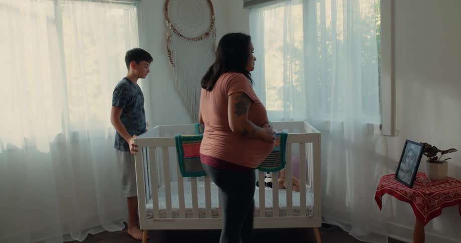 A mother hugs a son by a crib