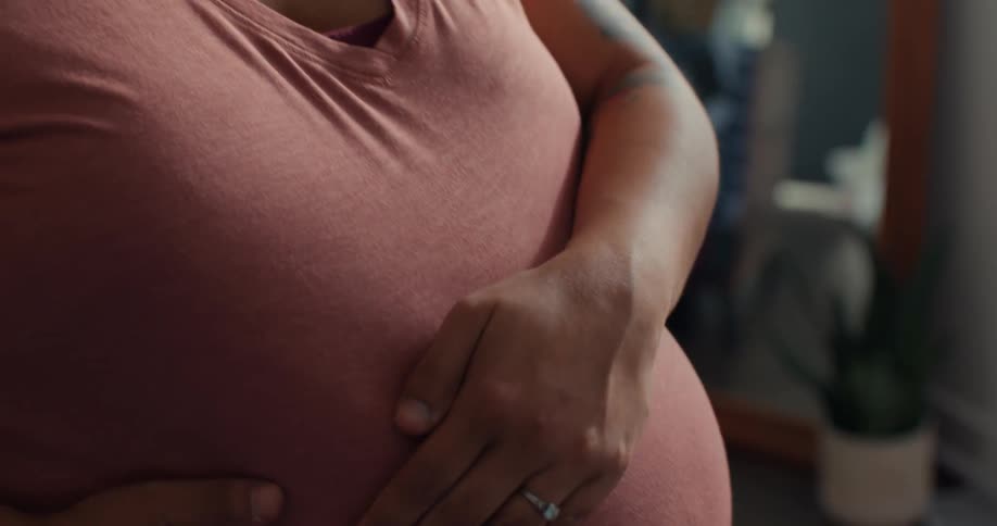 Woman rubbing hand across her very pregnant belly