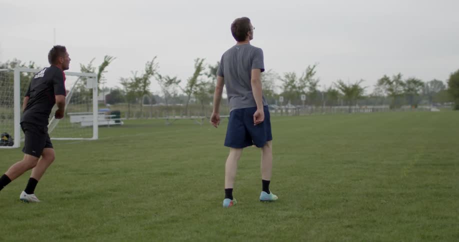 A man kicks a soccer ball and runs off