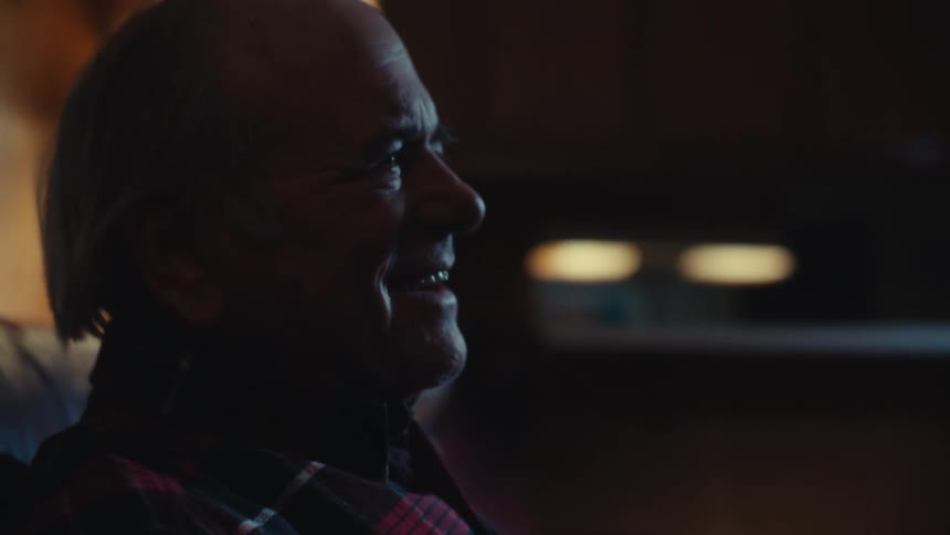Elderly man sitting at home at night enjoys the television