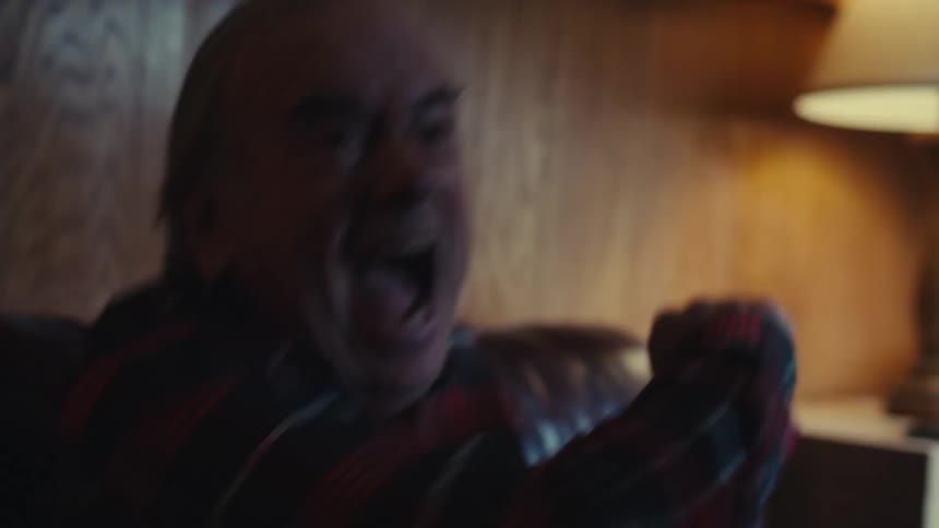 A man holding a remote cheers at the television
