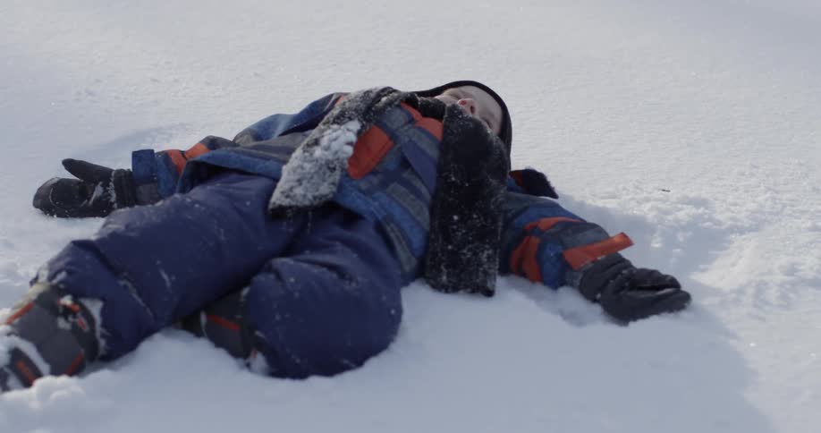 A boy is doing snow angels