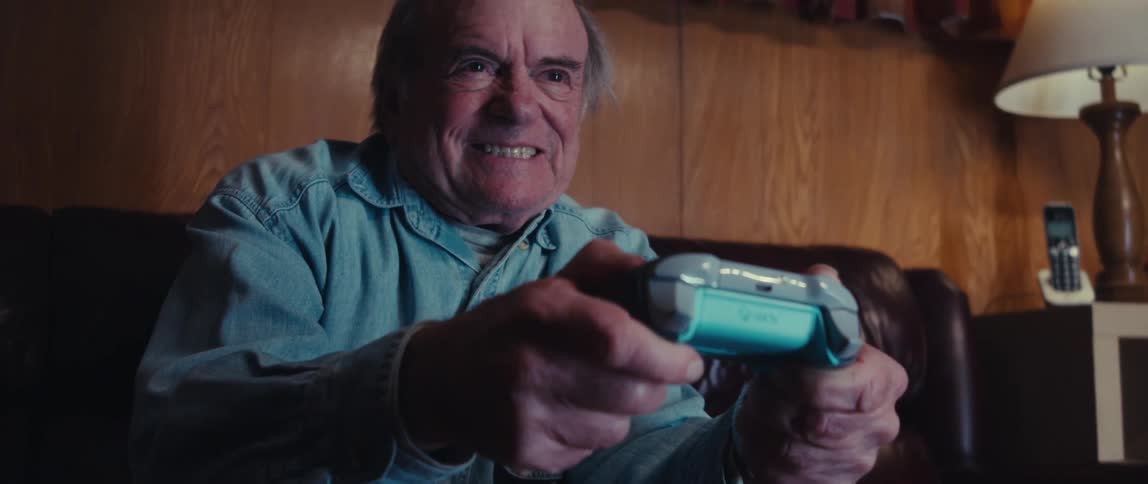 An elderly man is excitedly playing video games at home