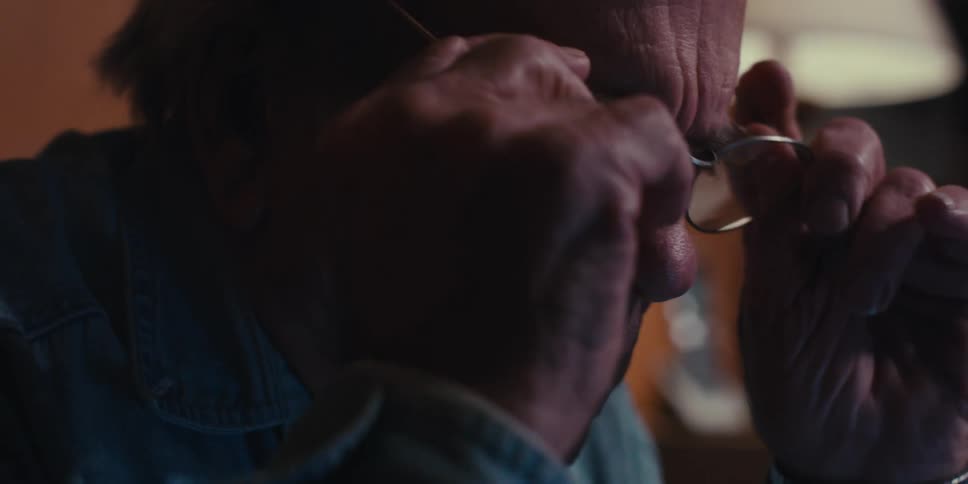 A close up clip of an elderly man putting on a glass