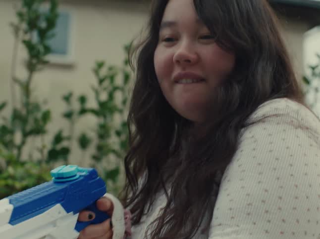 Girl holding a toy gun and playing in the yard