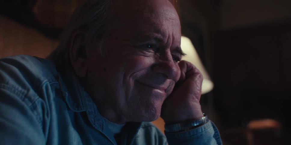 Elderly man putting his hand to his face and having a happy facial expression