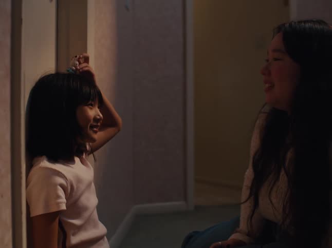Mother and daughter sitting on the floor in the hallway balance a toy on their heads