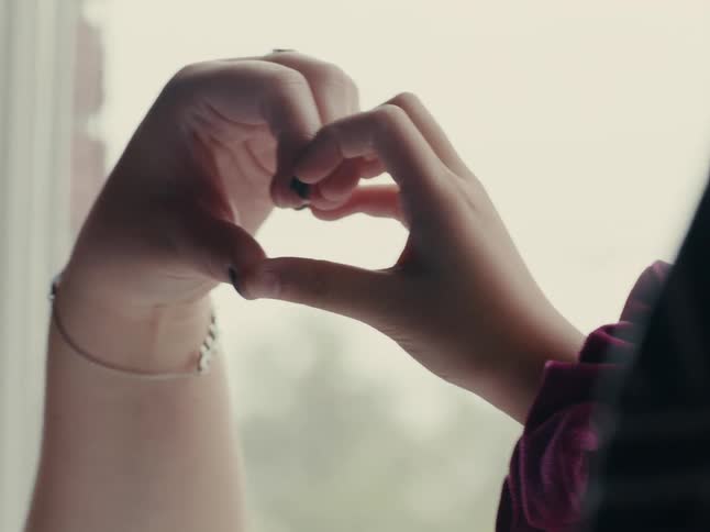 A closeup of hands with scrunchies around their wrists playing in front of a window