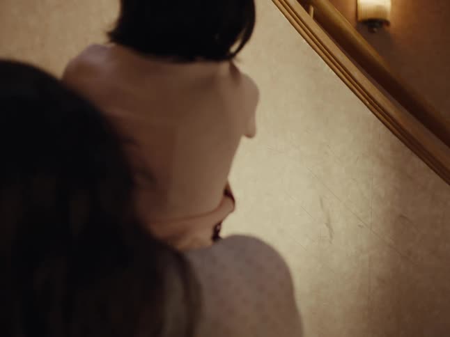 Teenager holding a little girl on her lap who is sticking a drawing on the wall