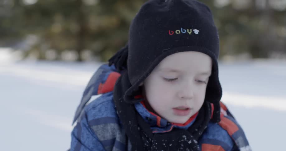 A child is using a shovel while playing in the snow