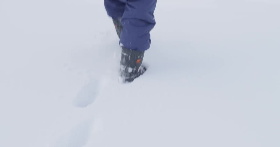 A child is walking in deep snow