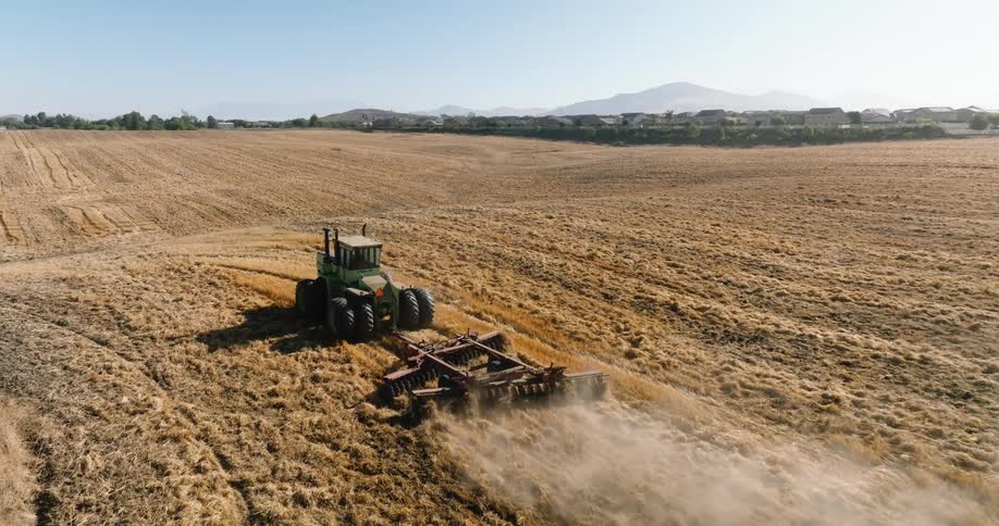 A tractor drags a plow through a field