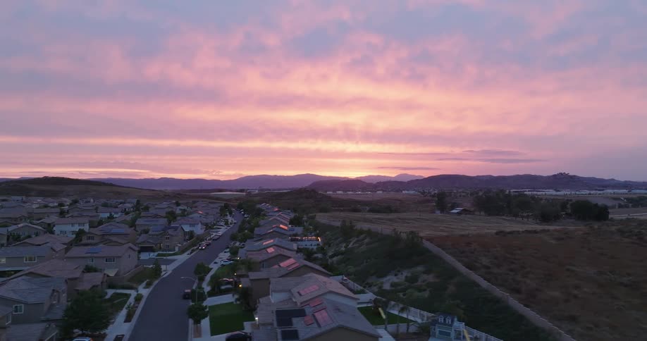 Aerial view of a residential neighborhood on a purple morning sky with mountains on the horizon